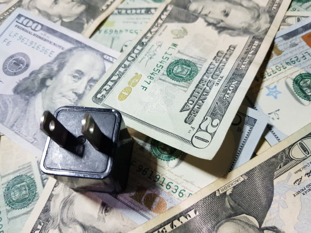 Power plug placed on top of U.S. dollars, Shutterstock ID#1411089932