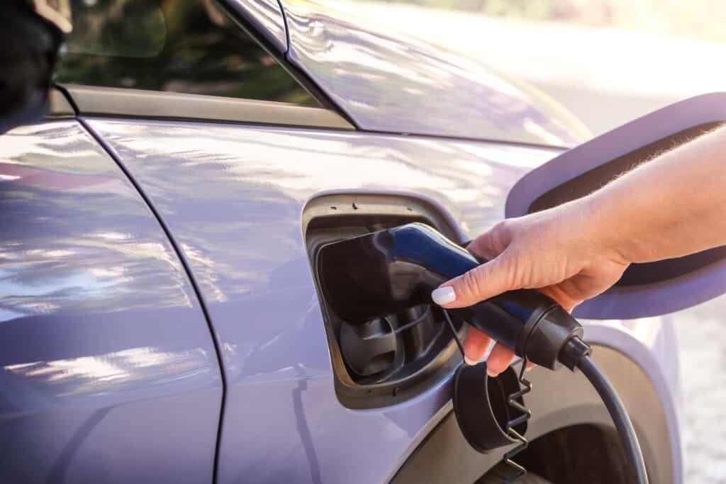 Woman charging an electric vehicle (EV), Shutterstock ID#2478902225