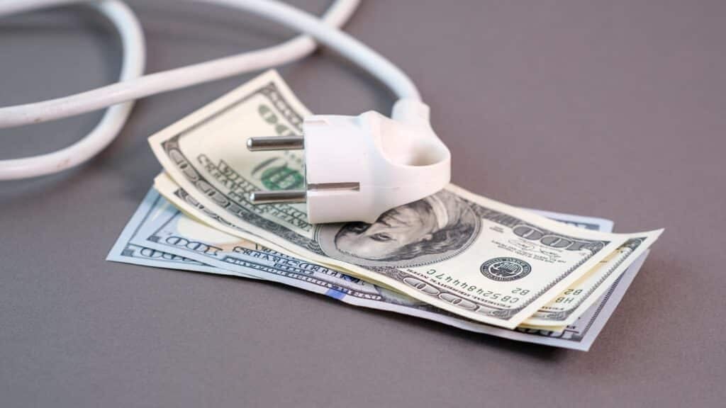 Dollars and a power strip illustrating high electricity prices and the rising cost of household energy during the utility crisis, Shutterstock ID#2719436007
